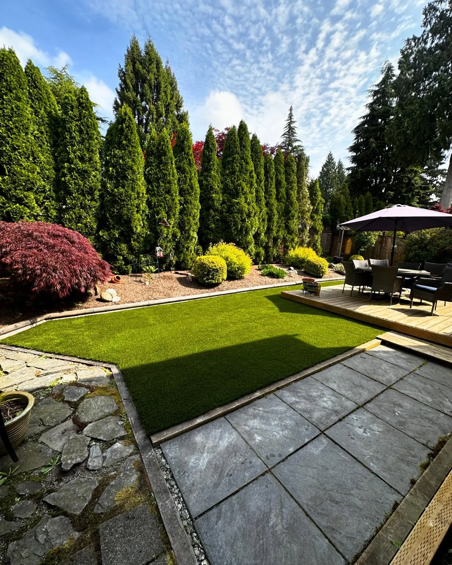 Completed Luxury Lawns artificial turf garden bordered by paving, a patio and mature trees